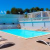 Piscina circondata da sdraio e cabine bianche.