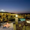 Ristorante all'aperto di sera con tavoli apparecchiati e vista su piscina illuminata.