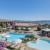 Una piscina con ombrelloni bianchi e viste panoramiche sul mare e montagne.