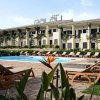 Piscina circondata da sdraio davanti a un edificio color crema con scritta 