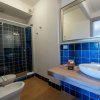 Bagno moderno con piastrelle blu, lavabo su piano in legno e doccia con pareti in vetro.