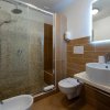 Moderno bagno con doccia, lavabo tondo e piastrelle marroni.