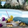 Vassoio con drink, biscotti e tovaglia blu a bordo piscina.