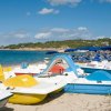 Pedalò colorati sulla spiaggia con ombrelloni blu e mare sullo sfondo.
