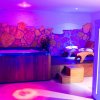 Una stanza con Jacuzzi e lettino relax, illuminata da luci colorate.