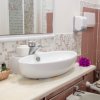 Bagno con lavabo ovale, asciugamani e piastrelle rosa.