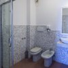 Bagno moderno con box doccia trasparente, wc, bidet e lavabo su piano in pietra chiara.