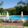 Piscina con ombrelloni e sedie su patio in legno.