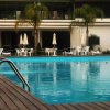 Piscina con bordo in legno e sedie a sdraio bianche.