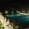 Piscina illuminata di notte con sedie a sdraio e ombrelloni.