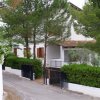 Villa bianca circondata da alberi e siepi.