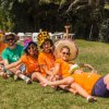 Gruppo di persone sorridenti con cappelli colorati sedute sull'erba.
