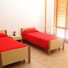 Camera con due letti singoli, coperte rosse.