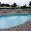 Piscina con terrazza in legno e ombrelloni.