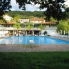 Piscina grande con edificio e sedie a sdraio intorno.