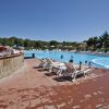 Piscina con nuotatori e sedie a sdraio bianche su un bordo bagnato, vista panoramica.