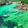 Barca su acqua verde cristallina circondata da costa rocciosa.