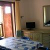 Sala con tavolo coperto, sedie blu, specchio e piccolo TV, porta aperta verso un balcone.