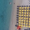 Ombrelloni gialli allineati su una spiaggia con mare trasparente.