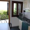 Cucina compatta con un piano cottura, tavolo e finestra che si apre su un balcone con piante verdi.