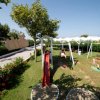 Parco giochi con altalene e scivolo su prato verde.