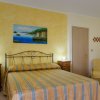 Camera con letto a righe, parete gialla e dipinto.