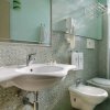 Bagno moderno con mosaico verde e sanitari bianchi.