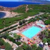 Vista aerea di un complesso con piscina, ombrelloni colorati, mare e vegetazione circostante.