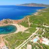 Vista dall'alto di una costa con spiaggia, vegetazione e mare blu.