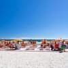 Spiaggia con sdraio, mare e cielo blu.