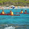 Persone in kayak su acque azzurre vicino alla spiaggia.