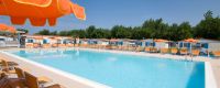 Ampia piscina all'aperto con ombrelloni e sedie a sdraio.