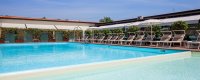 Piscina con sedie a sdraio coperte da tende bianche.