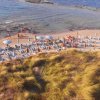 Spiaggia con ombrelloni blu e bianchi.
