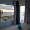Camera con vista sul mare, palme e tramonto.