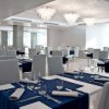 Un elegante ristorante con tavoli apparecchiati con tovagliette blu e sedie bianche.