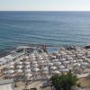 Una spiaggia affollata con ombrelloni bianchi vicino a un mare blu.