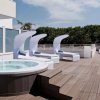 Terrazza con vasca idromassaggio e lettini sotto il cielo azzurro.