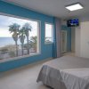 Camera con vista mare, letto bianco, pareti azzurre e grande finestra.