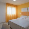 Camera da letto con pareti gialle, letto matrimoniale e tende arancioni.