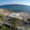 Vista dall'alto di una spiaggia affollata con ombrelloni e mare.