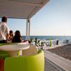 Due persone sedute a un tavolo colorato vicino alla spiaggia, con vista sul mare.