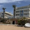 Edificio moderno a più piani con palme e accesso a un tunnel su una spiaggia sabbiosa.