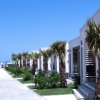 Bungalow moderni lungo un viale con palme.