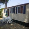Casa mobile chiara con finestre blu, tavolo e sedie bianche all'esterno.