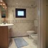Bagno con lavabo, specchio, wc e finestra piccola, pavimento piastrellato.