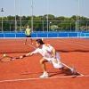 Due persone giocano a tennis su un campo all'aperto in terra rossa.