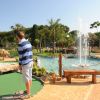 Ragazzo gioca a minigolf vicino a una fontana.