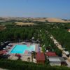 Piscina all'aperto circondata da alberi e colline sullo sfondo.