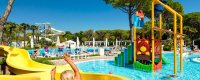 Parco acquatico con scivoli gialli e giochi colorati, persone in piscina.